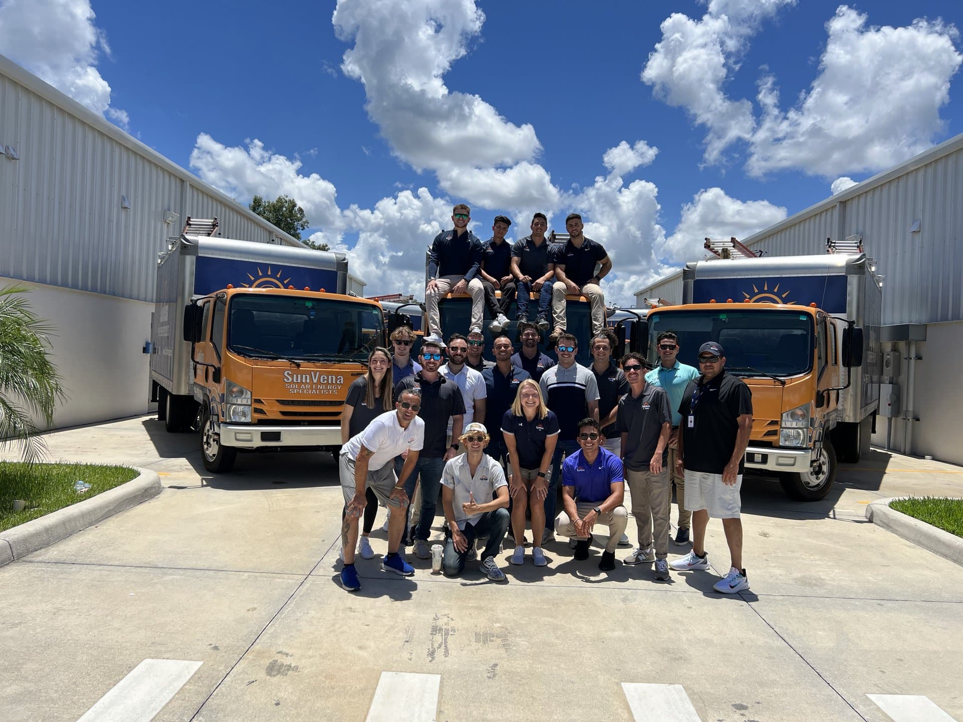 The full Team MegaWatts crew in front of two SunVena Solar trucks at HQ